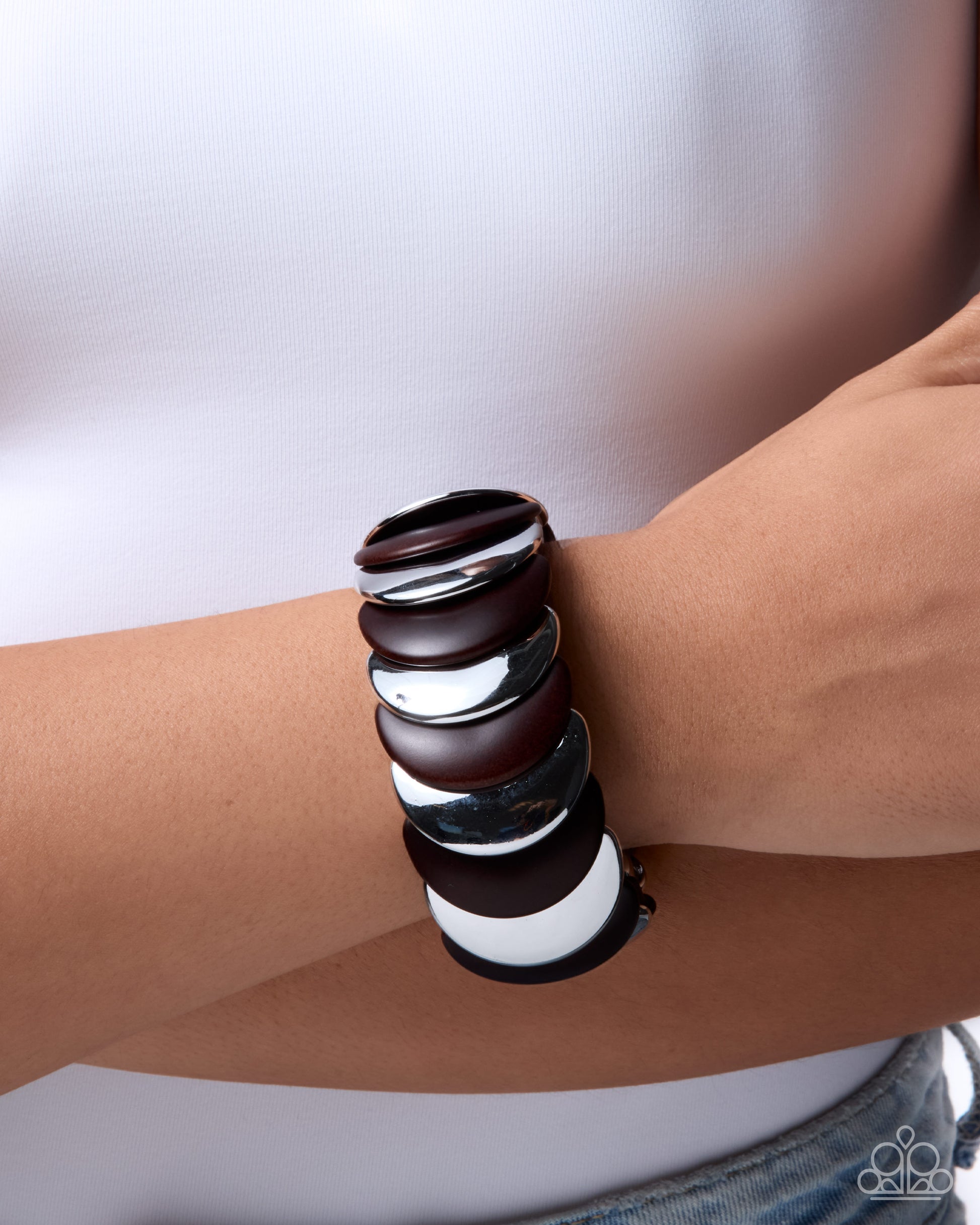Stacked leather bracelets on a wrist against a neutral background