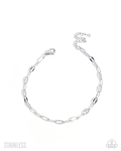 A silver stainless steel paperclip chain bracelet with a lobster clasp, displayed on a clean white background with a 'STAINLESS' text overlay in the bottom left and a small logo in the bottom right.