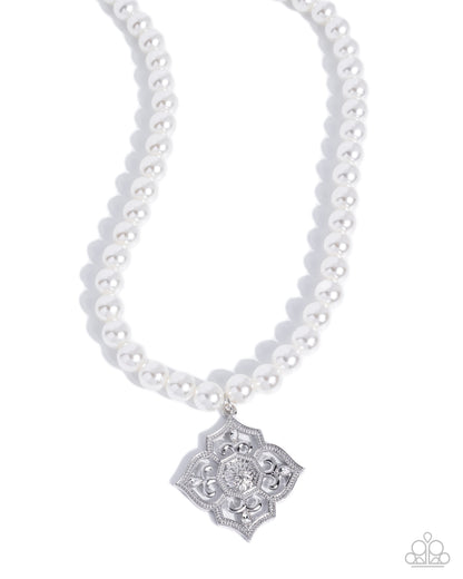 A white pearl necklace with a silver filigree pendant featuring a clear central stone, shown on a clean white background.