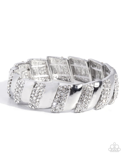 A wide silver-toned band ring featuring alternating raised rectangular panels and diagonal striped sections, all embellished with clear rhinestones, photographed on a white background.