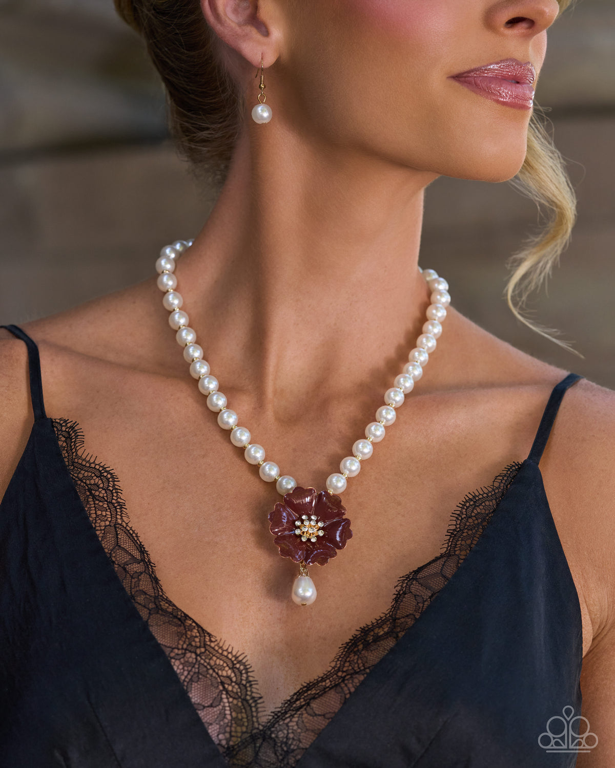 A close-up lifestyle shot of a woman wearing a pearl necklace with a dark burgundy flower-shaped pendant and a matching pearl drop earring.