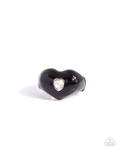 A glossy black heart-shaped ring with a small silver heart-shaped bezel holding a clear rhinestone, shown on a plain white background.
