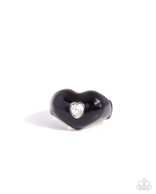 A glossy black heart-shaped ring with a small silver heart-shaped bezel holding a clear rhinestone, shown on a plain white background.