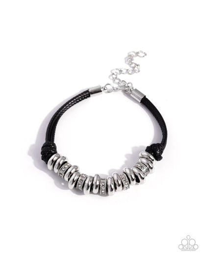 A black braided cord bracelet featuring a row of textured silver disc beads with clear rhinestones, a silver metal clasp, and an adjustable silver chain extender, shown on a white background.