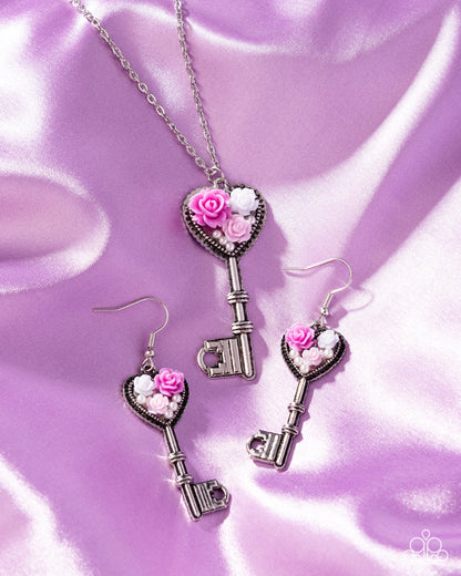 Key-shaped jewelry set with pink roses on a purple satin background