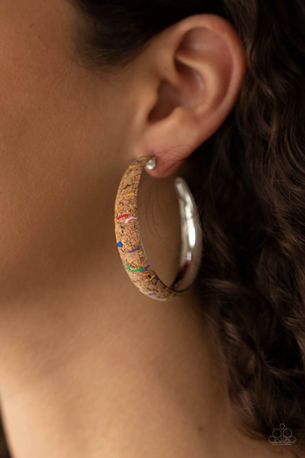 Silver hoop earring with cork-like texture worn by a person