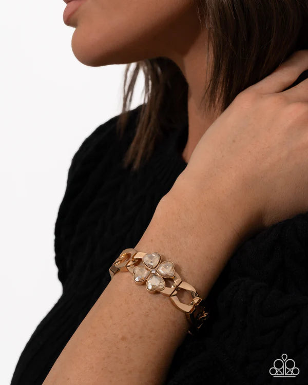 Gold bracelet with clear stones on a wrist against a neutral background