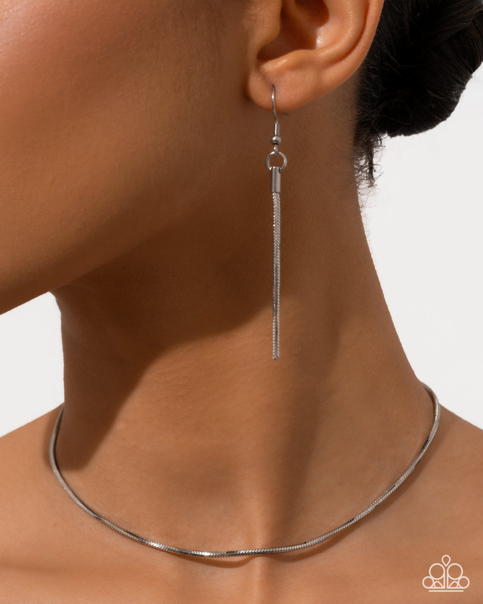 Silver earring worn by a person with a plain background