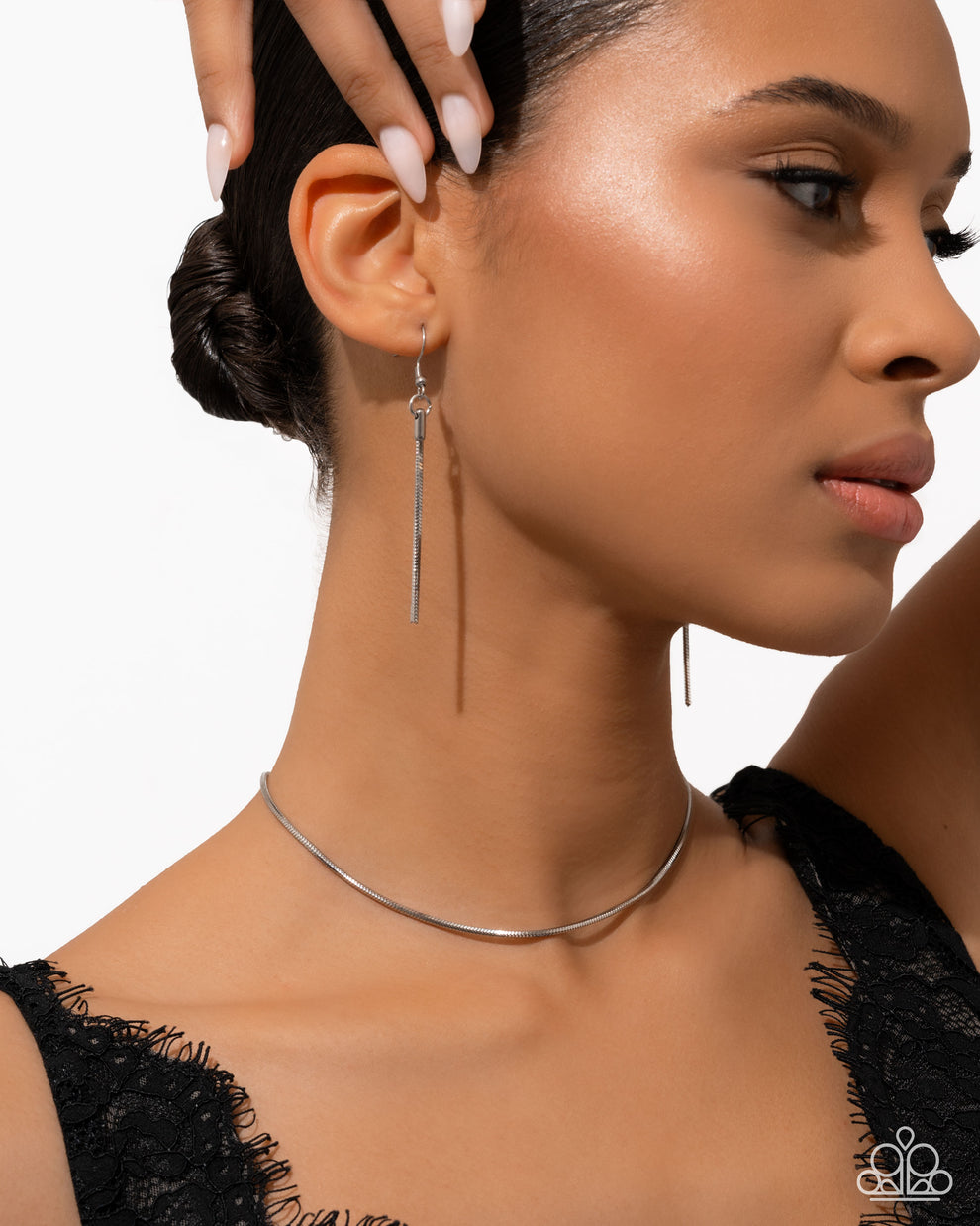 Close-up of a woman wearing silver earrings and a necklace against a white background