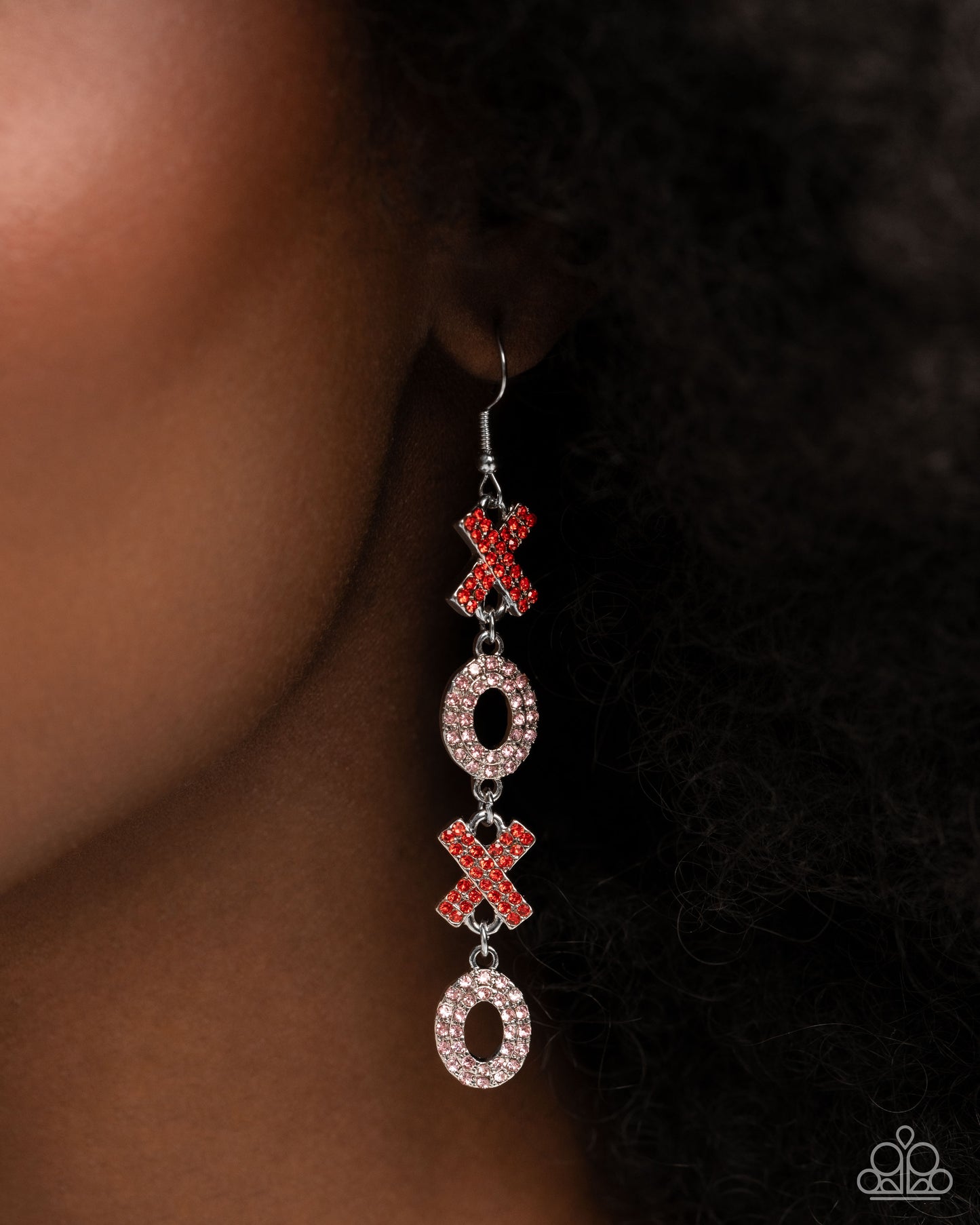 Earring with red and silver 'XO' design on a dark background