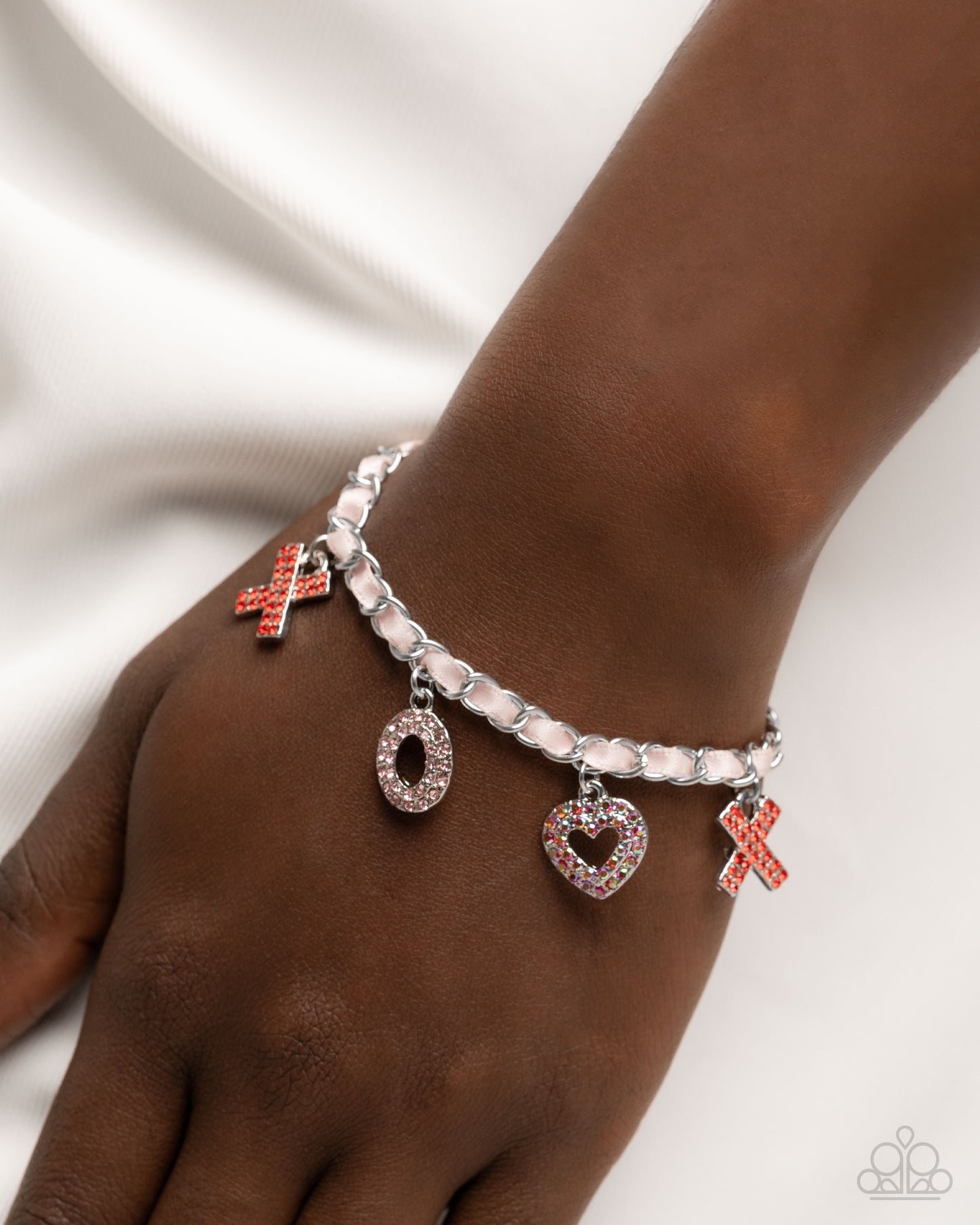 Bracelet with heart and cross charms on a wrist against a white background