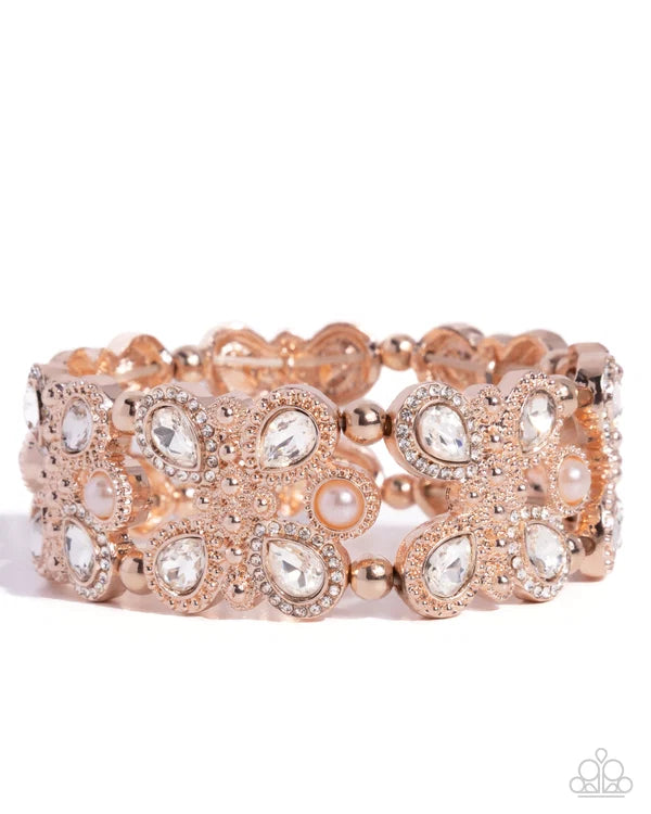Rose gold cuff bracelet adorned with clear crystals, faux pearls, and small gold beads on a white background.