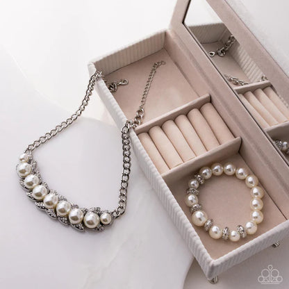 Pearl necklace and bracelet on an open jewelry box with compartments.