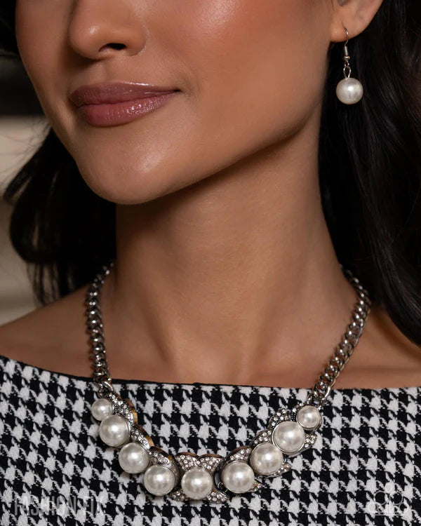Close-up of a woman wearing a pearl necklace and earrings with a blurred background