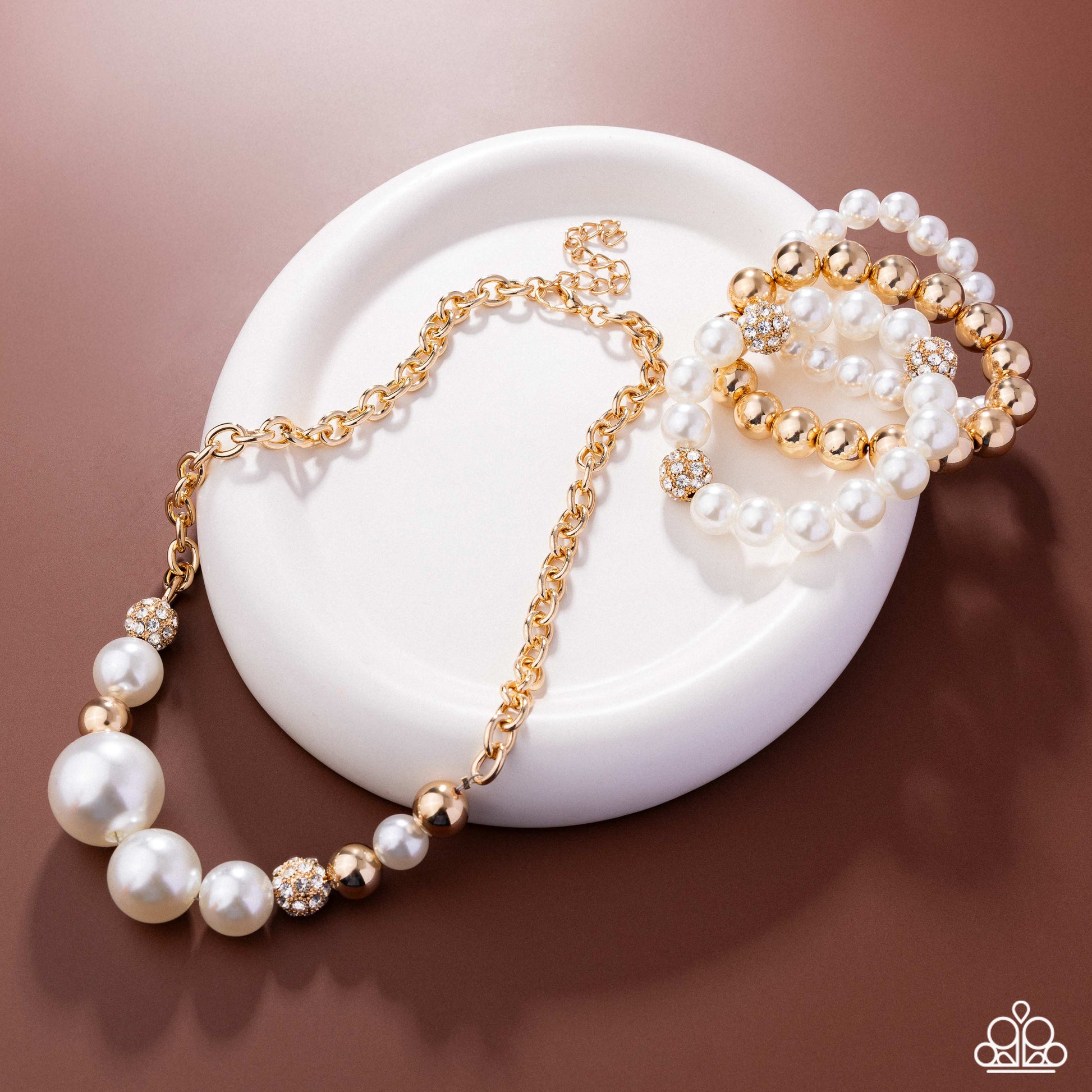 Pearl and gold necklace on a white dish with a brown background