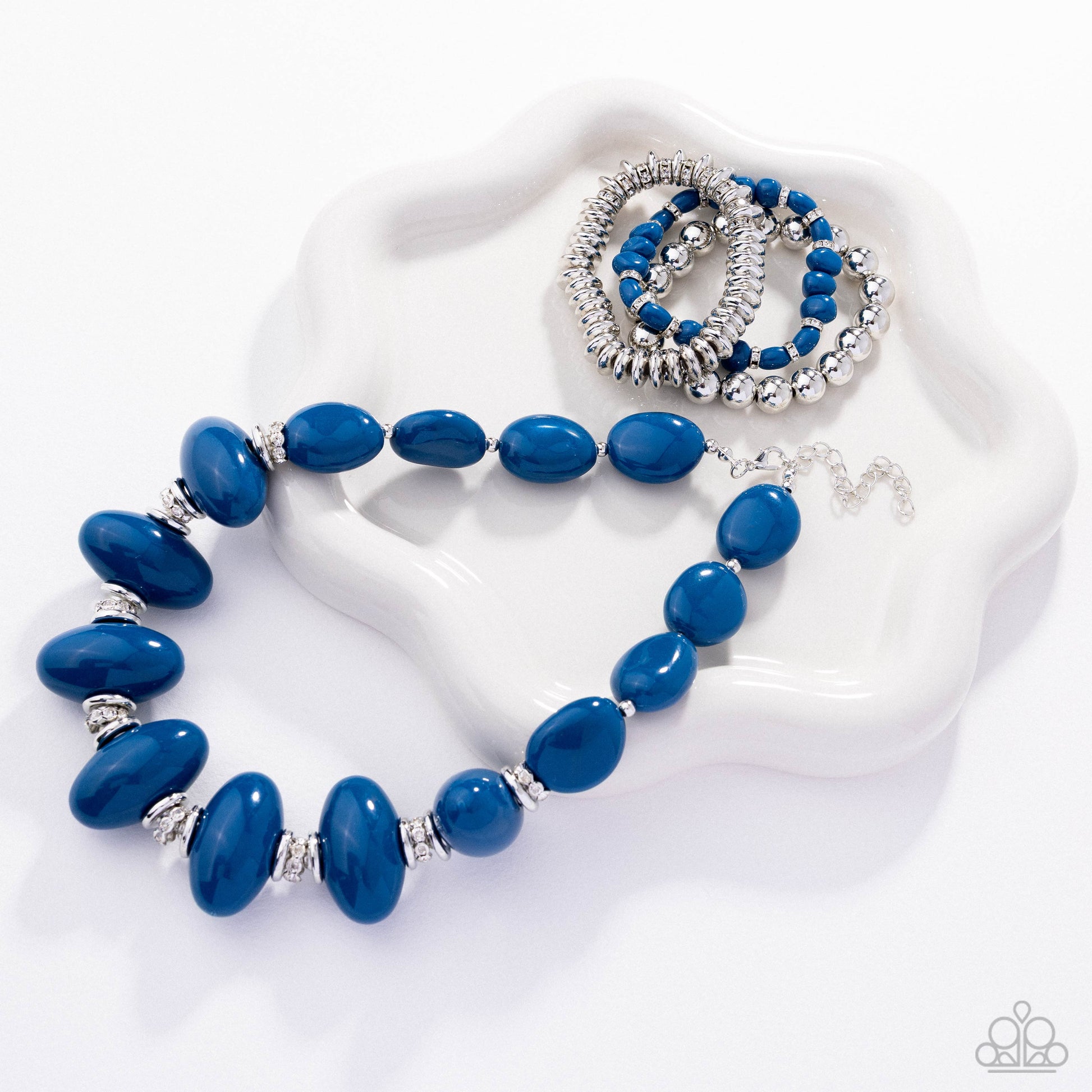 Blue beaded necklace with silver accents on a white heart-shaped stand