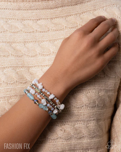 Hand wearing a beaded bracelet on a textured beige background