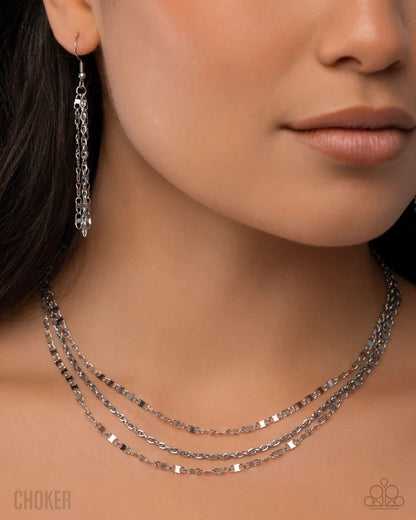 Close-up of a woman wearing silver chain choker necklace and earrings.