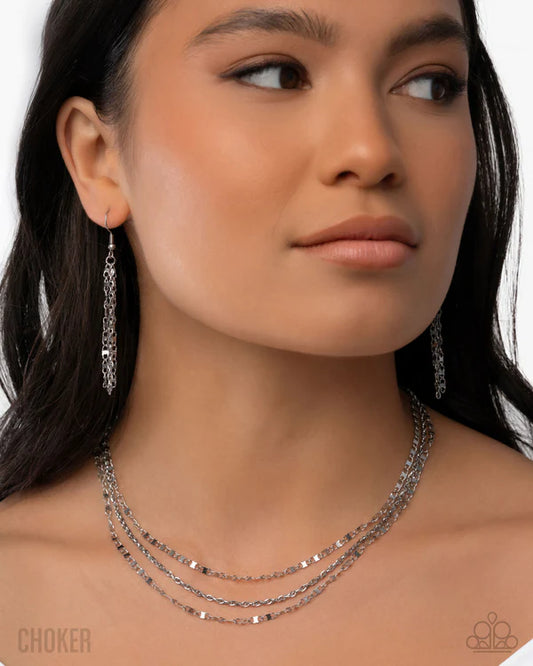 Woman wearing a silver chain necklace and earrings on a white background