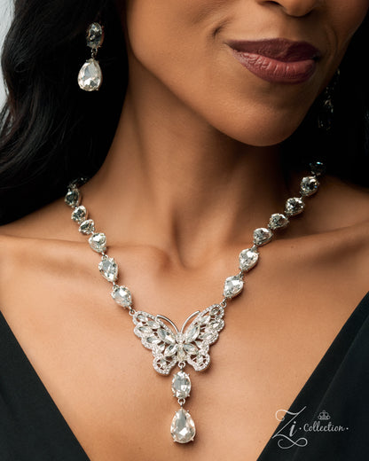 A close-up of a woman wearing a silver-toned butterfly pendant necklace with clear teardrop and round stones, matching drop earrings, and a black dress. The image has a watermark in the bottom right corner reading 'Li Collection.