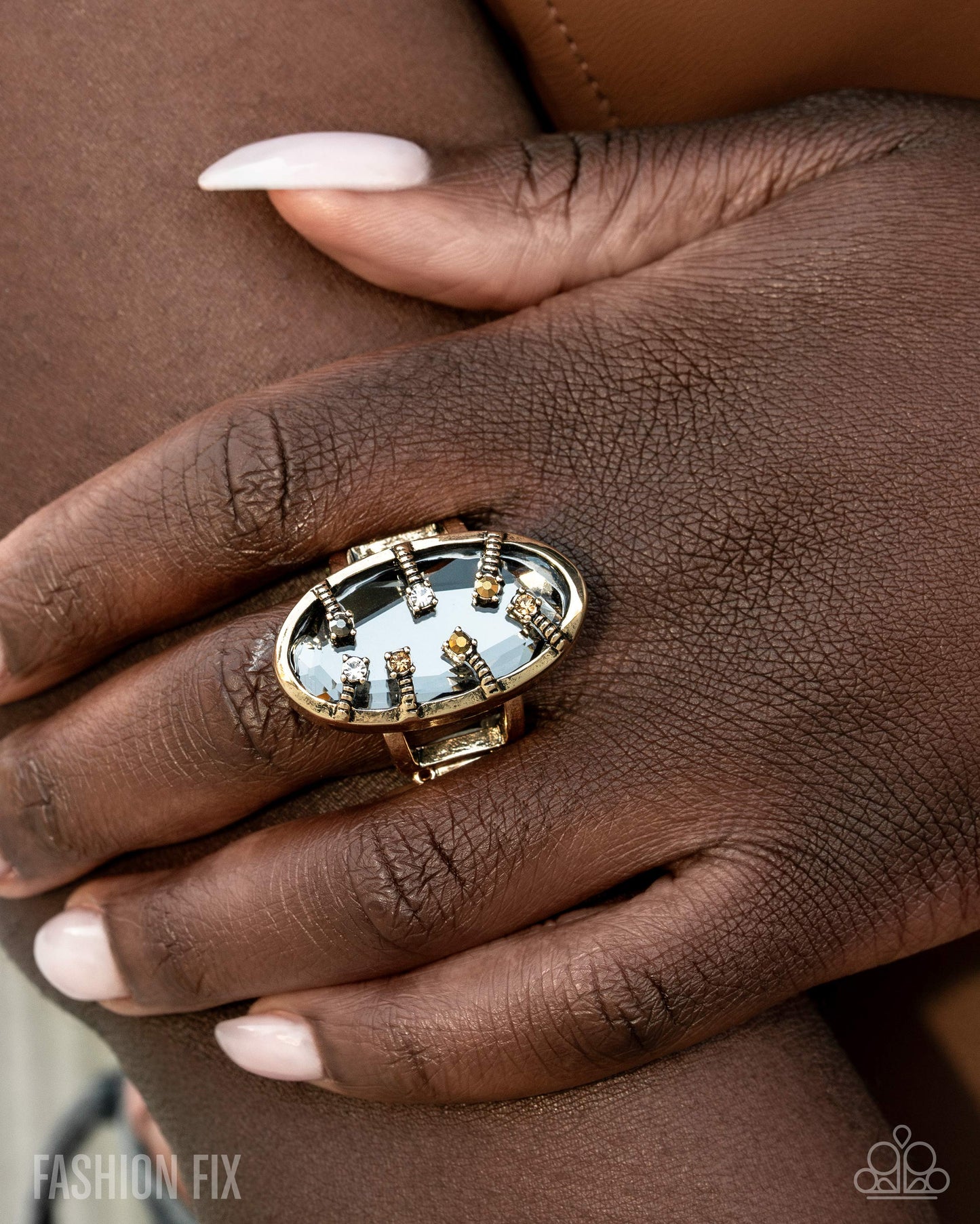 Close-up of a hand wearing a decorative ring with a gold and gemstone design.