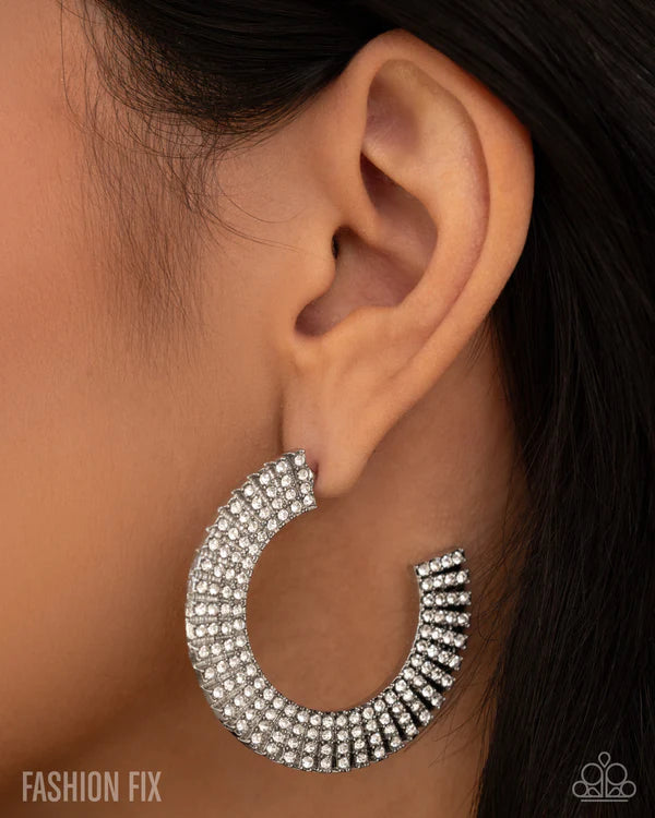 Silver hoop earring worn by a person with dark hair.