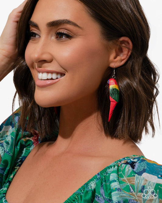 Woman wearing colorful earrings with a patterned top on a white background