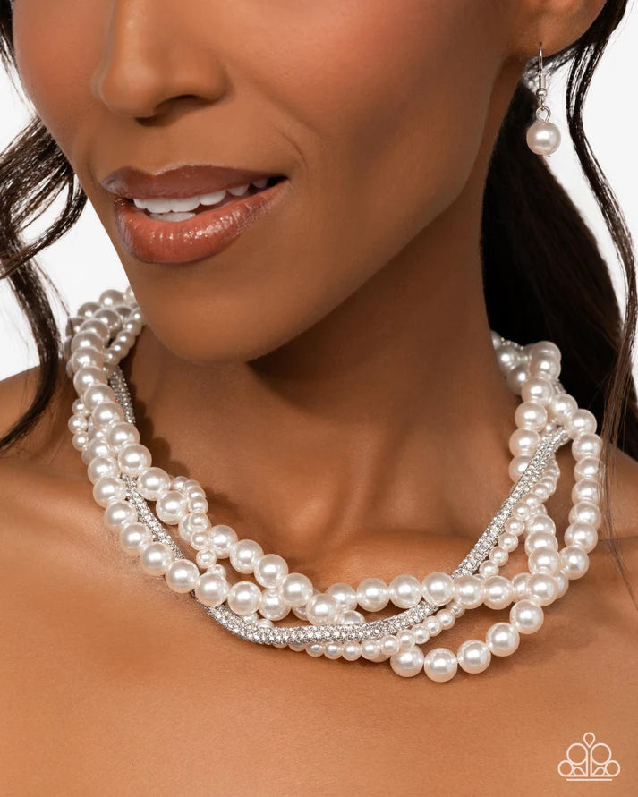 Close-up of a woman wearing a pearl necklace and earrings on a white background