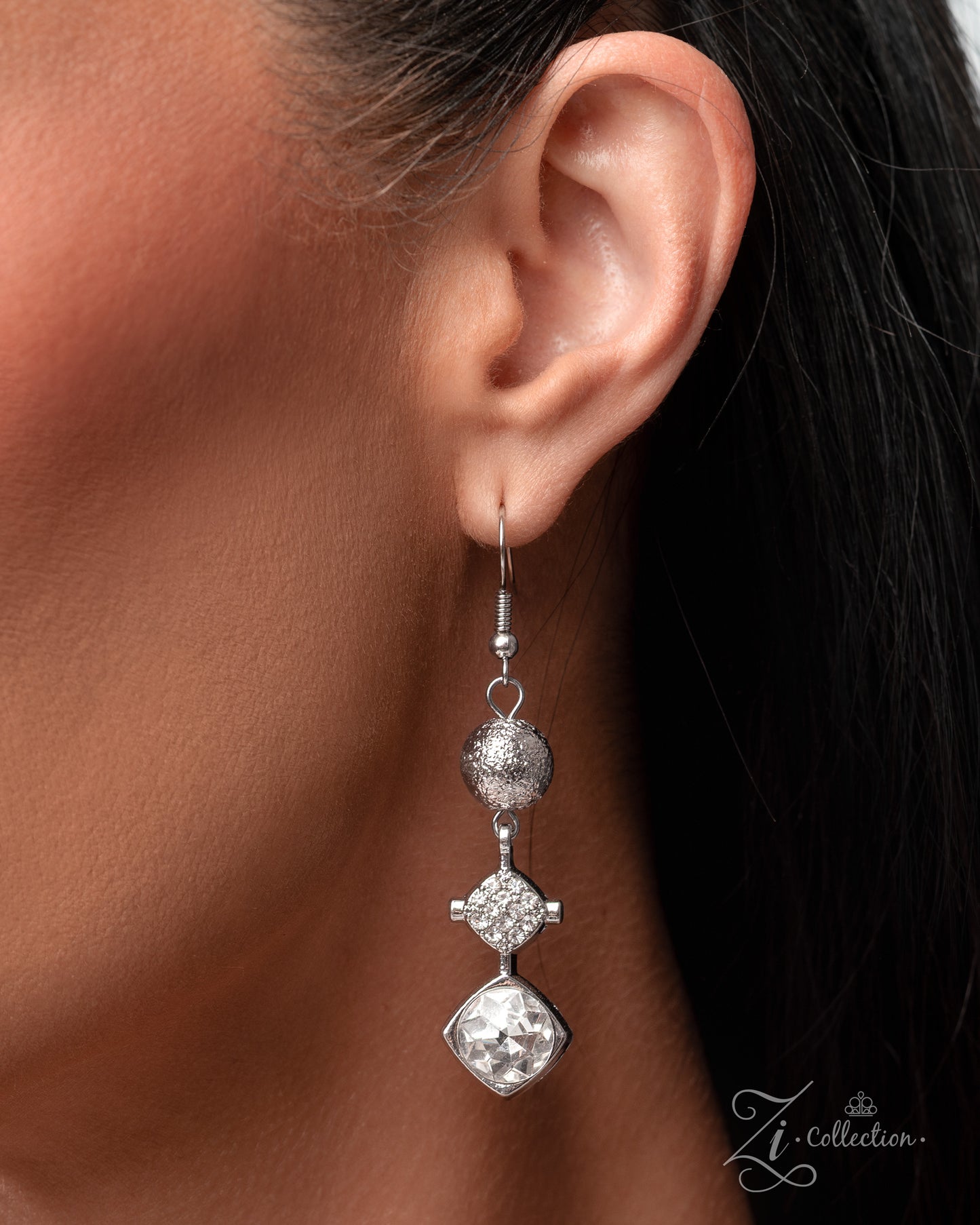 Silver earrings being worn, with a blurred background