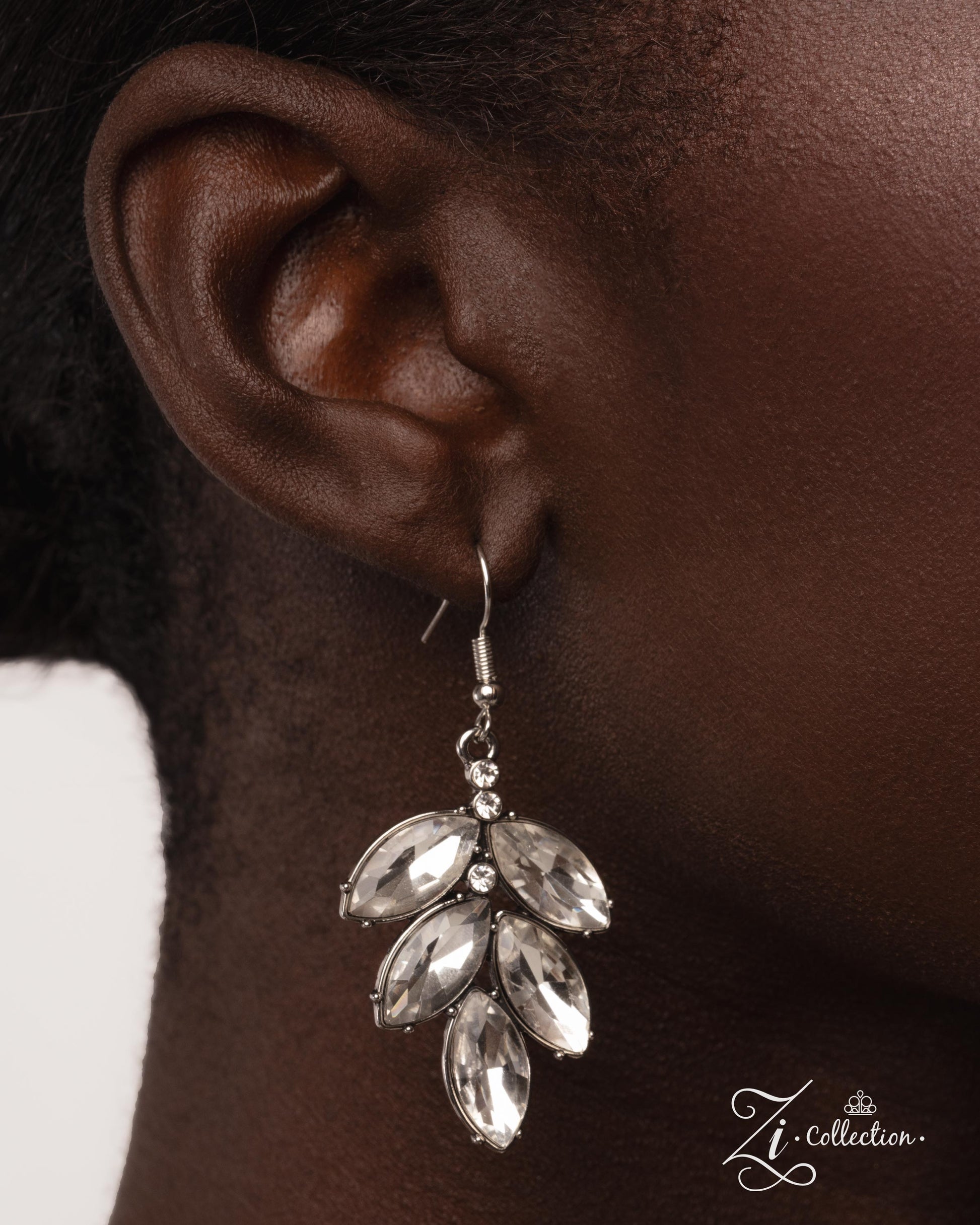 Silver leaf-shaped earrings worn by a person, with 'Zi Collection' branding.