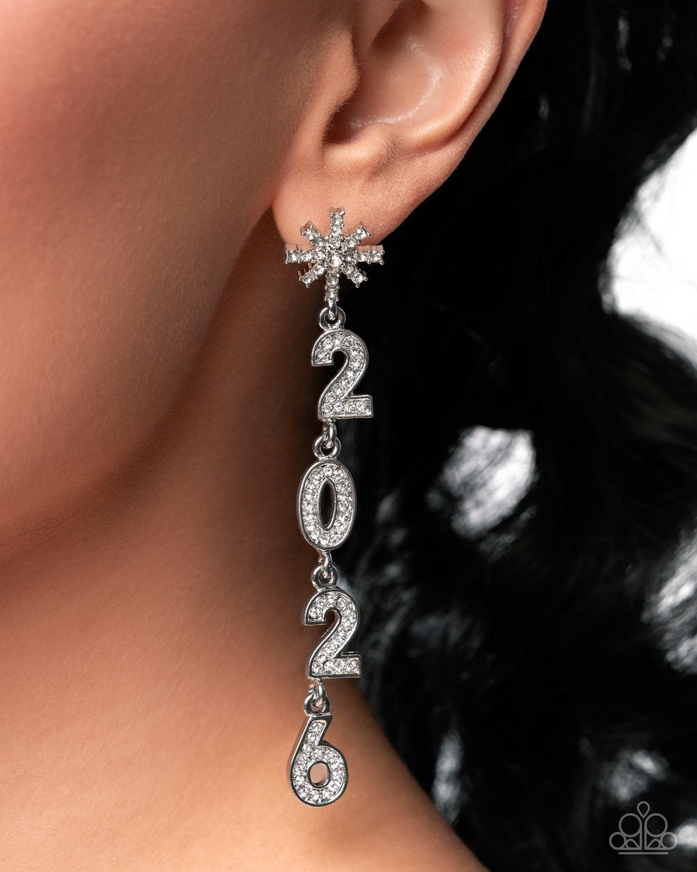 Silver '2026' earrings with snowflake design worn by a person.