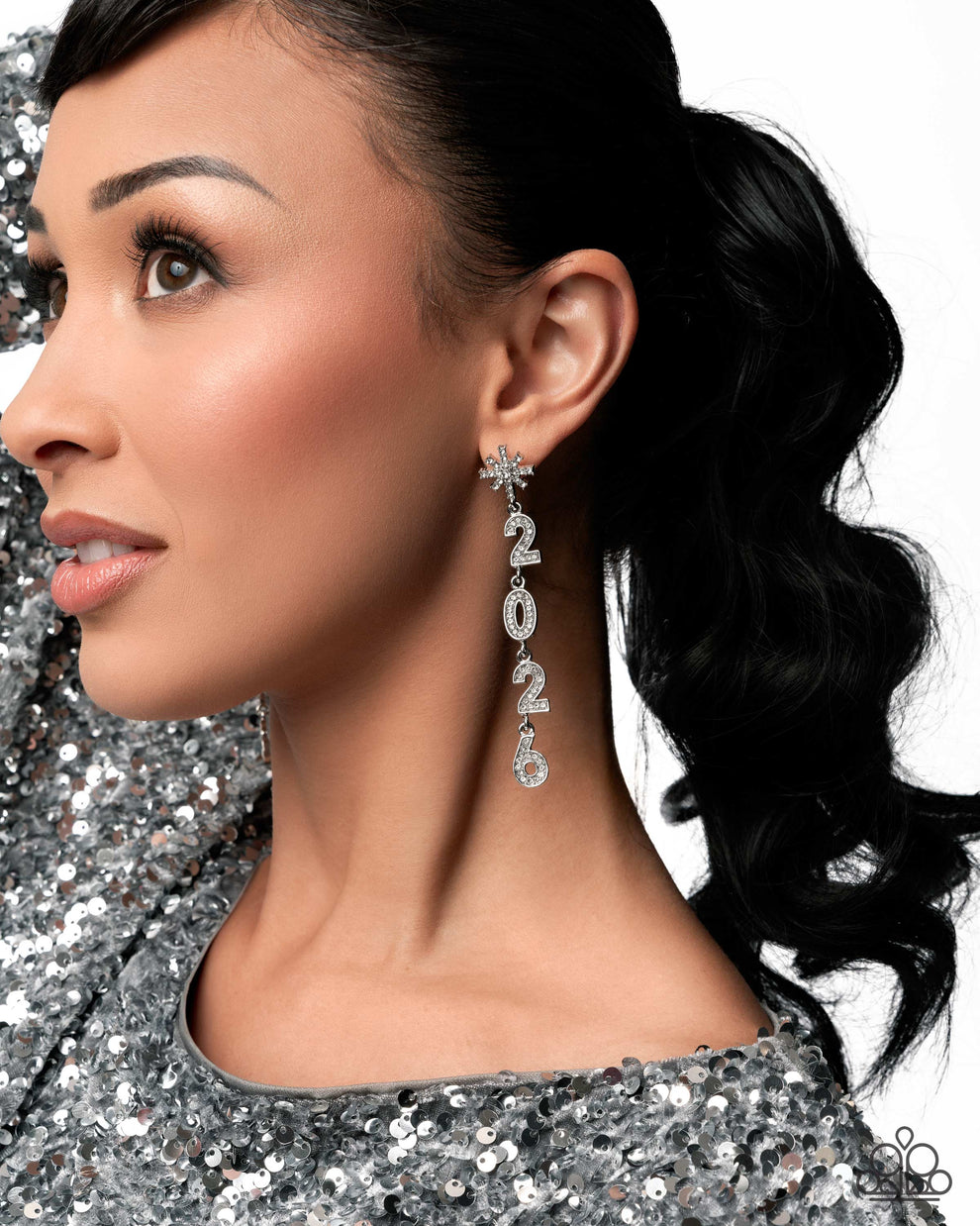 Woman wearing sparkling silver earrings with a sequined outfit on a glittery background