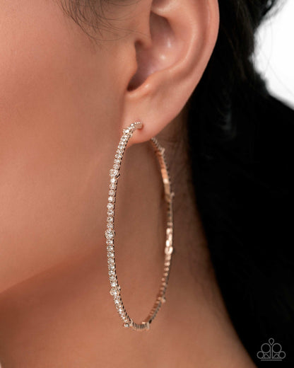 Rose gold hoop earring with clear stones worn by a person