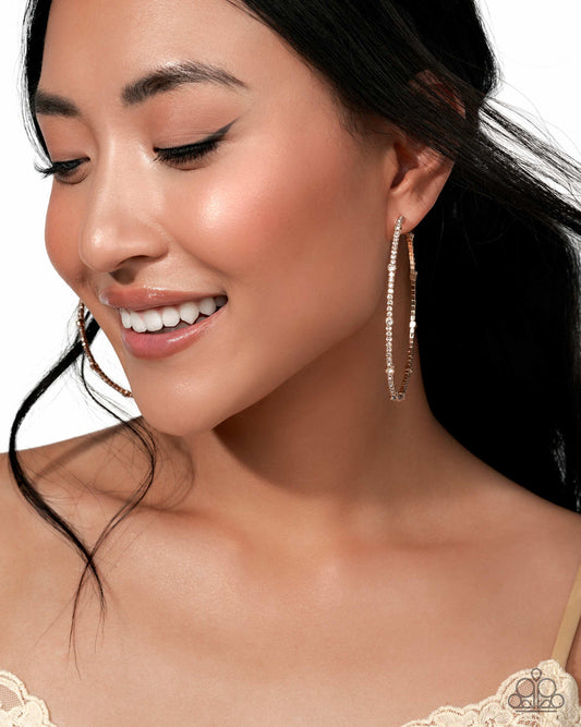 Close-up of a woman wearing large hoop earrings with a neutral background