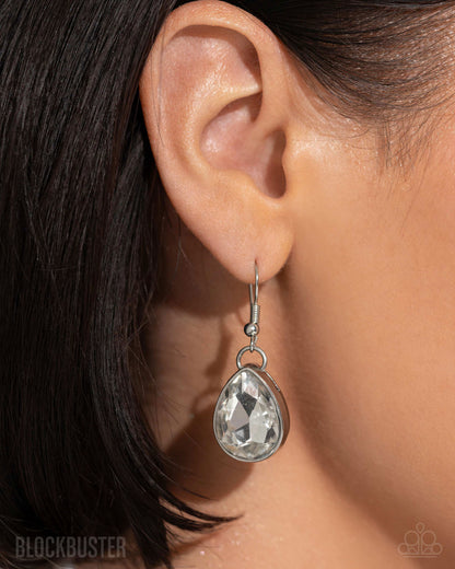 Teardrop-shaped earring worn on an ear with dark hair.
