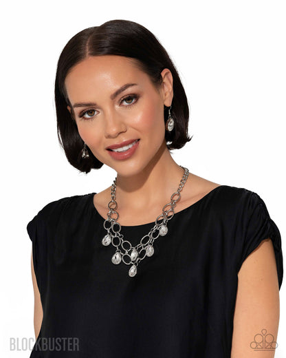 Woman wearing a black dress with a silver necklace and earrings on a white background