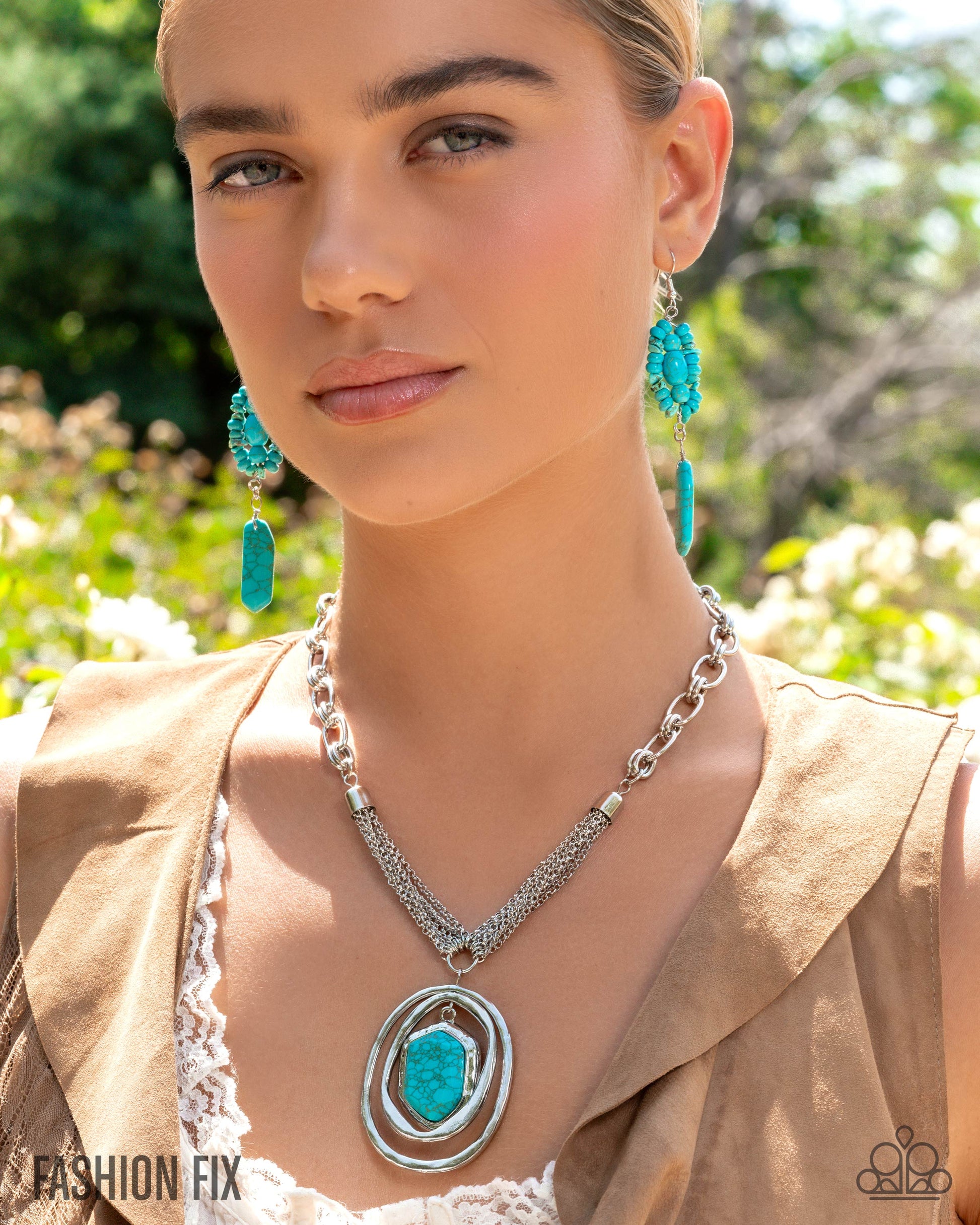 Woman wearing turquoise earrings and a necklace with a large pendant outdoors