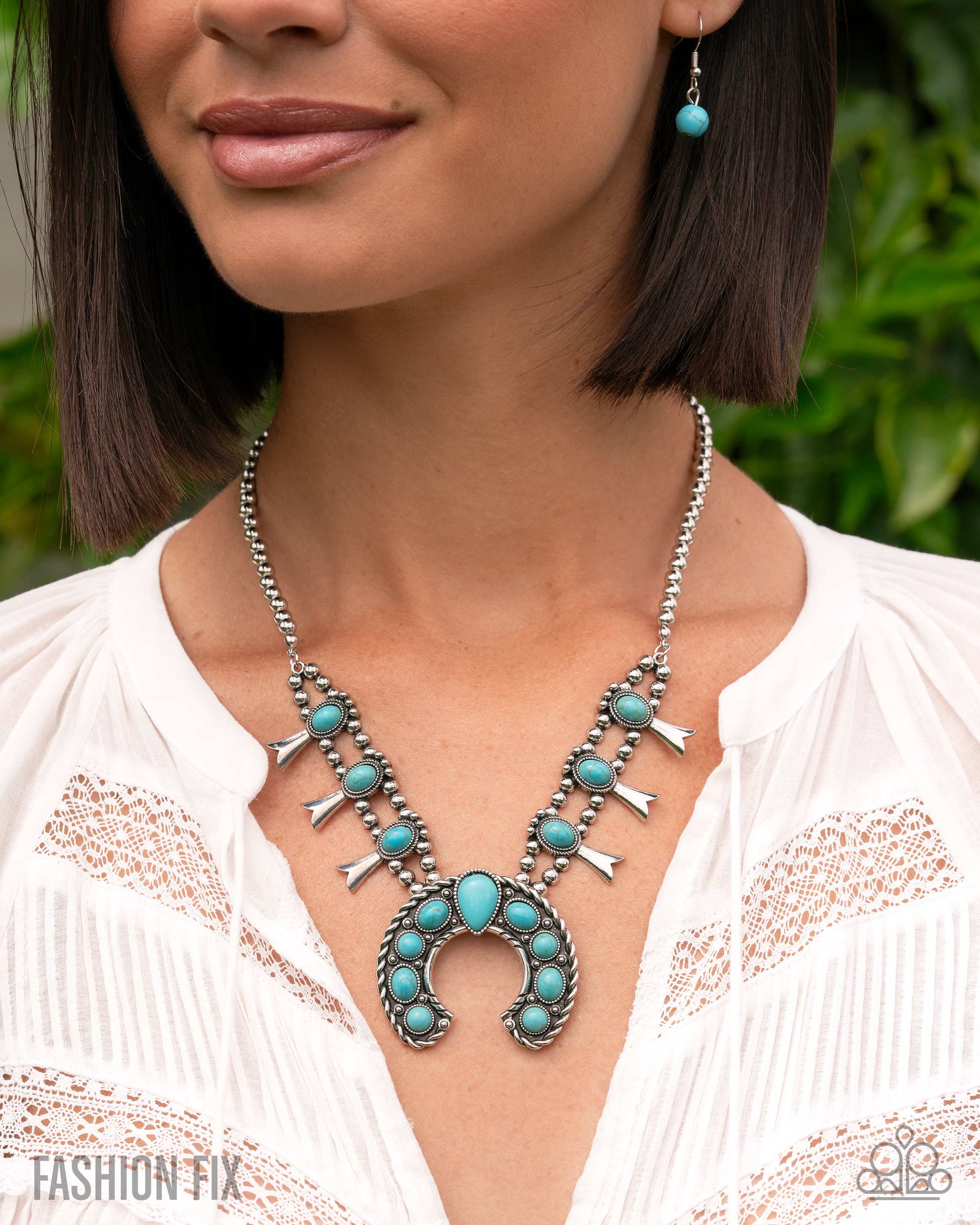 Woman wearing a turquoise and silver necklace with earrings, against a blurred green background.