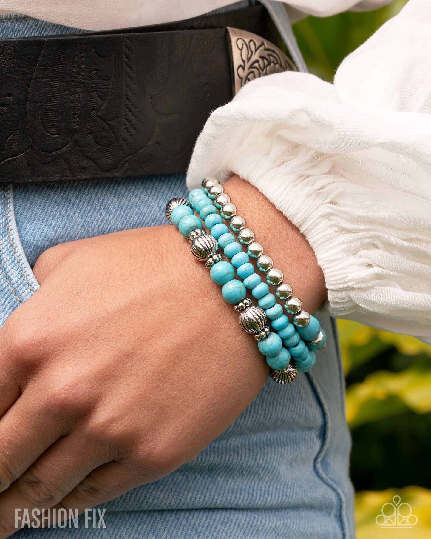 Turquoise beaded bracelet with silver accents on a wrist, with a blurred background.