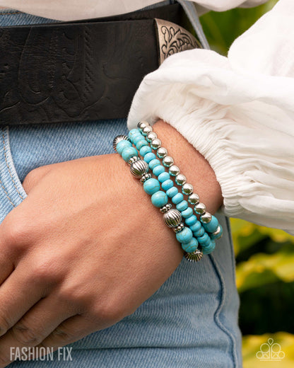 Turquoise beaded bracelet with silver accents on a wrist, with a blurred background.