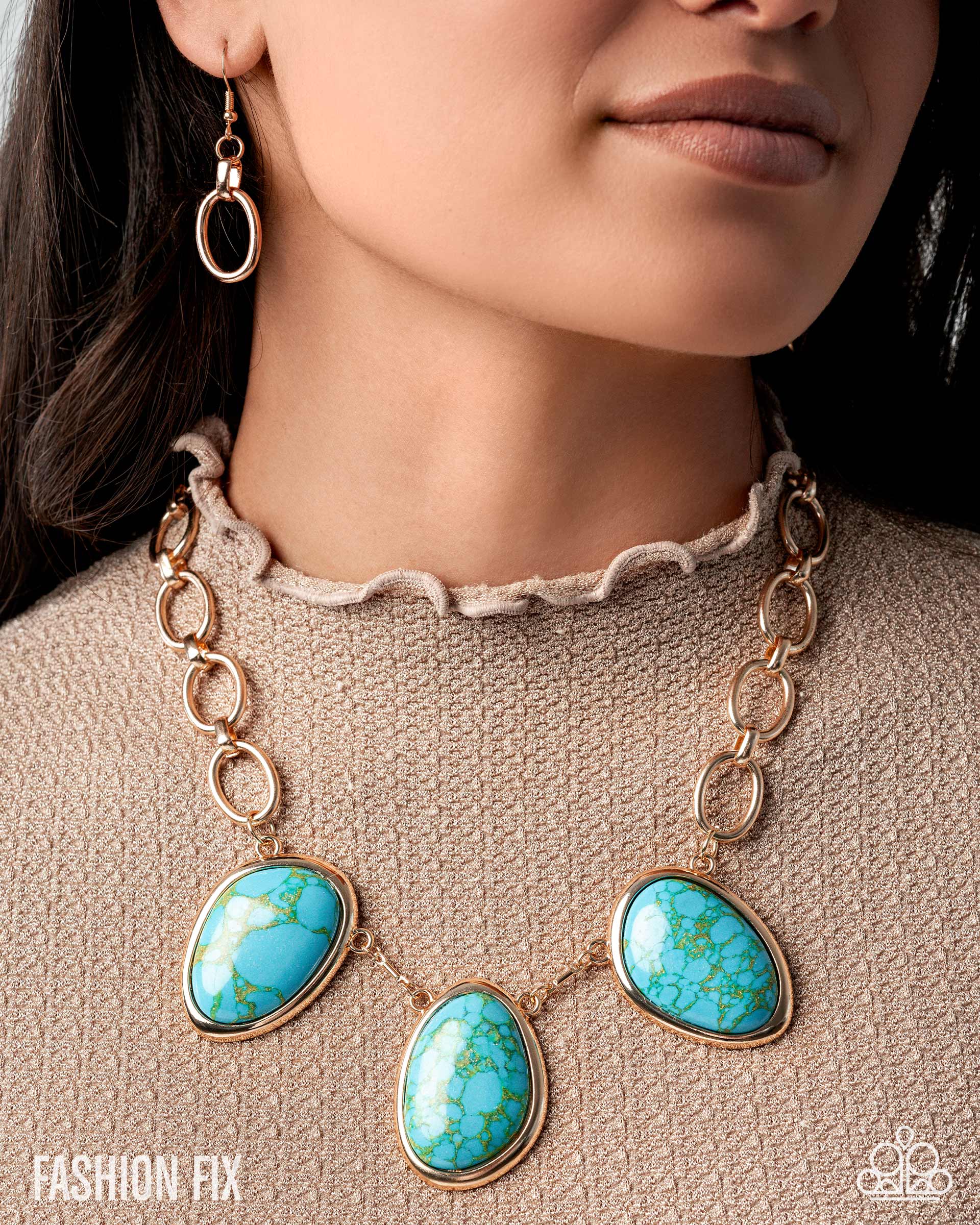 Necklace with turquoise stones and gold chain on a person wearing a beige sweater.
