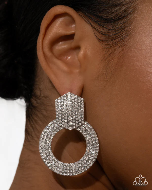 Silver hoop earring worn by a person with a neutral background