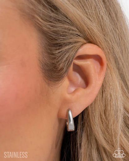 Silver hoop earring worn by a person with blonde hair.