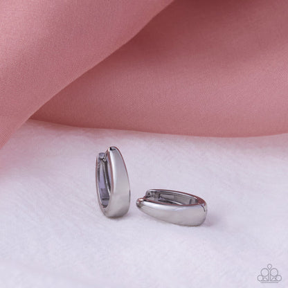Silver hoop earrings on a pink fabric background