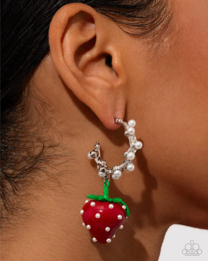 Close-up of an ear wearing a unique earring with a strawberry design.