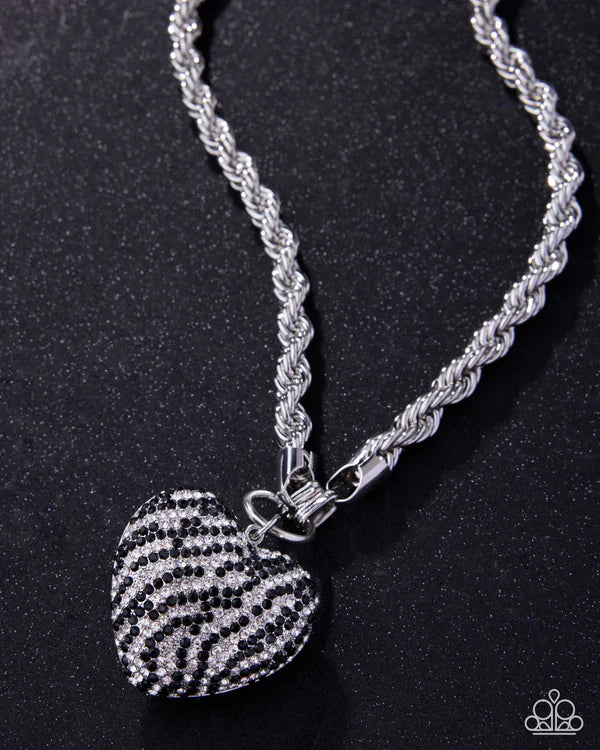 Silver necklace with a heart-shaped zebra print pendant on a black background