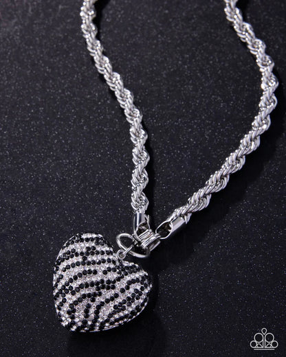 Silver necklace with a heart-shaped zebra print pendant on a black background