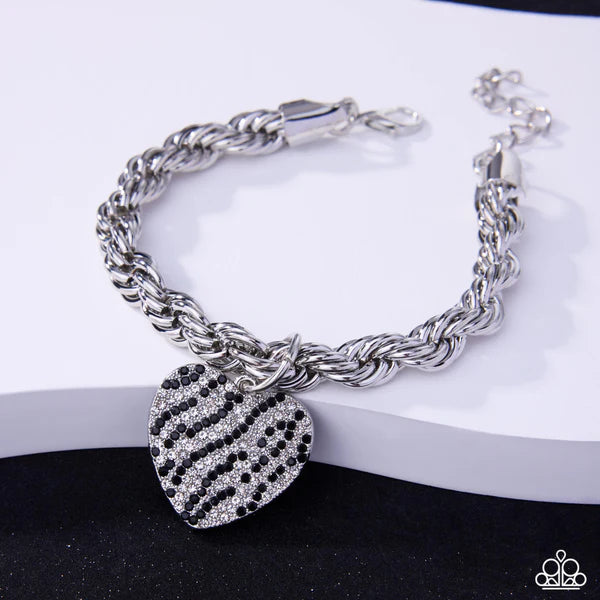 Silver bracelet with a heart-shaped charm on a white surface