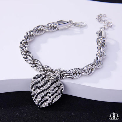 Silver bracelet with a heart-shaped charm on a white surface