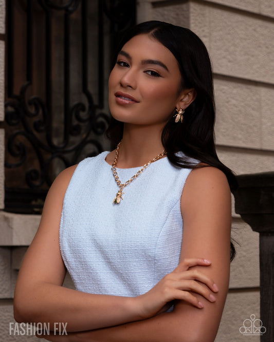 Woman wearing a light blue sleeveless top with gold jewelry against a neutral background